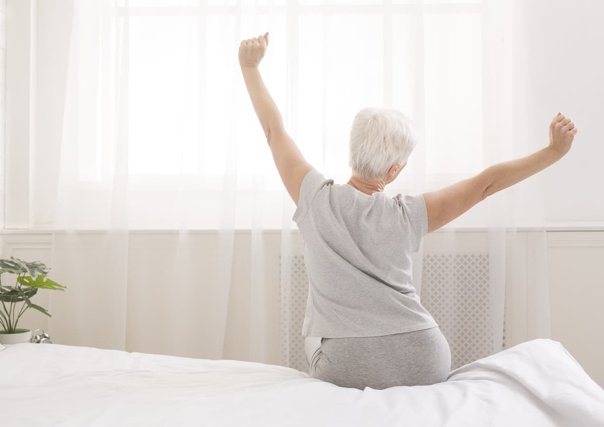 Senior woman sitting on her bed in morning