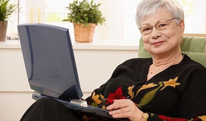 senior woman happily using a laptop