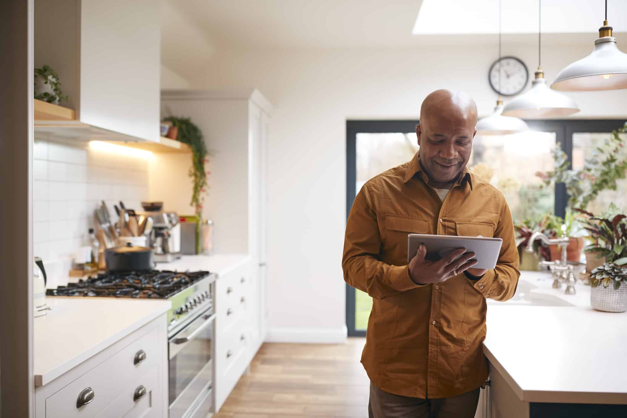 Man At Home In Kitchen Looking At Tablet