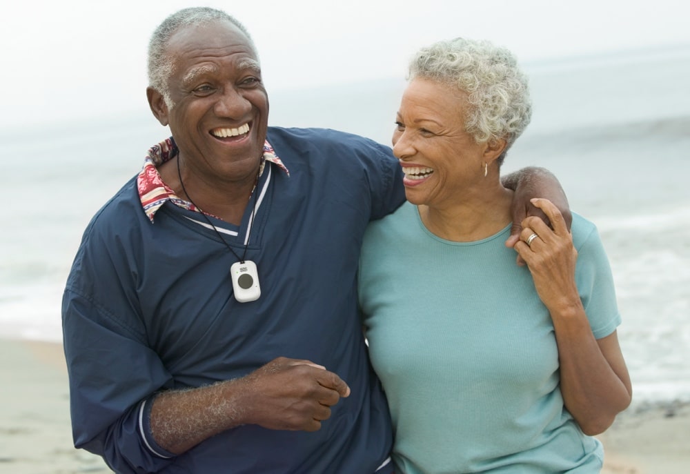 Couple on beach wearing On the Go medical alert system