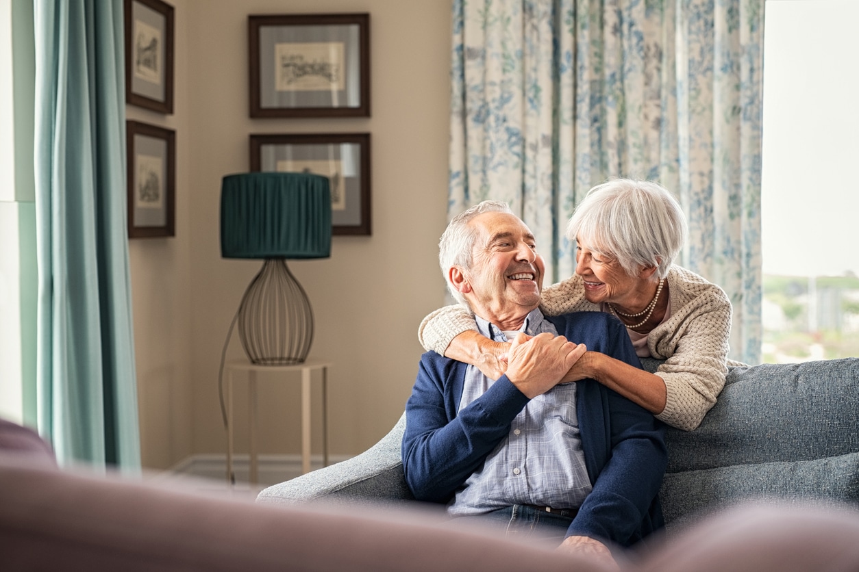 Senior couple sitting on couch smiling