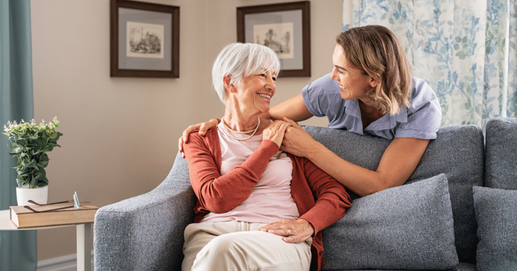 Older woman sitting with a caregiver on a sofa at home