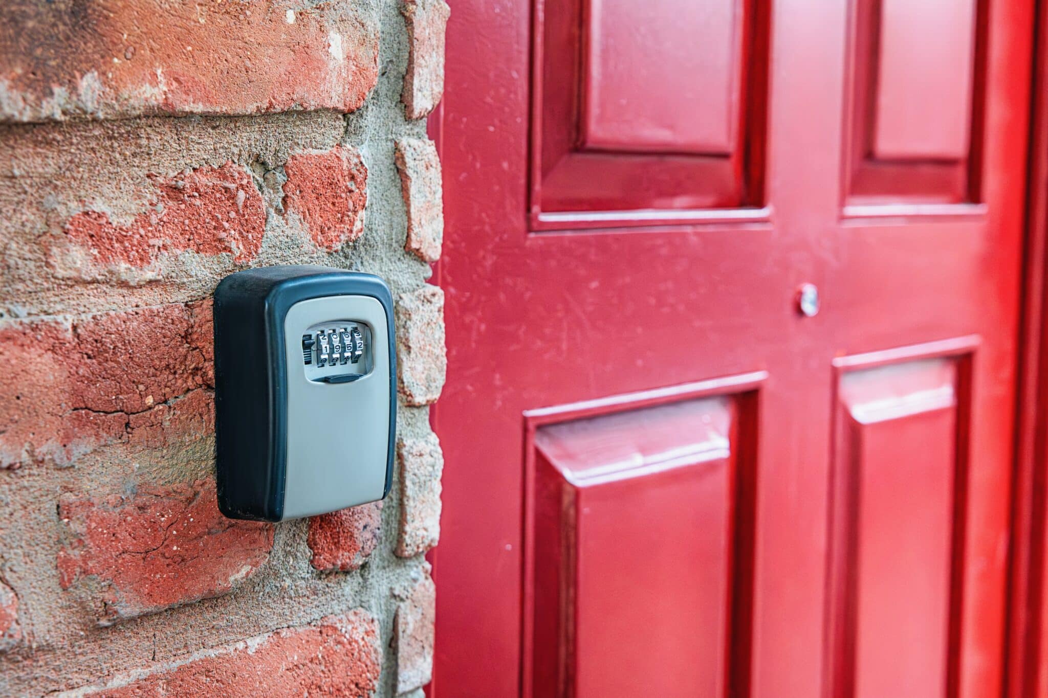 Secure key lockbox mounted beside the front door of a home