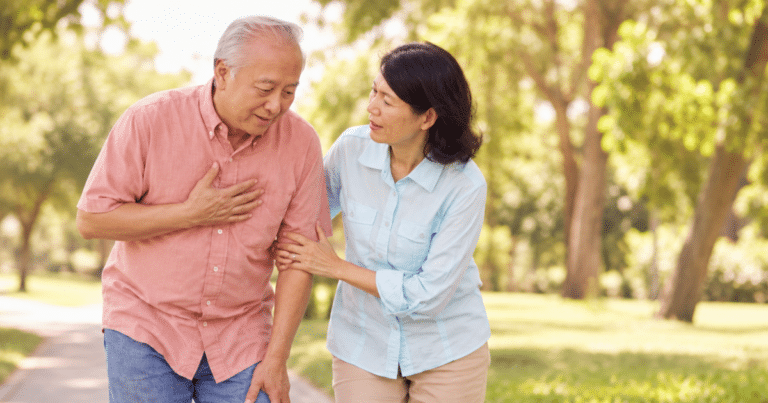 Heart attack warning signs in seniors as an older man pauses during a walk with his concerned spouse