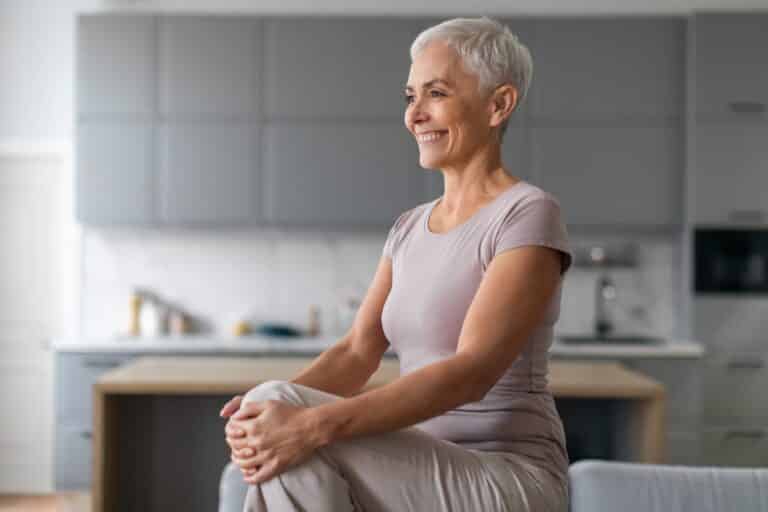 Senior woman practicing seated side stretches at home as part of core exercises for seniors.